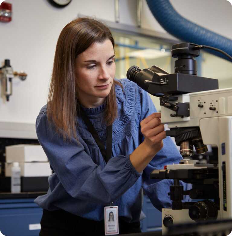A woman setting up a microscope to analyze samples in a controlled environment
