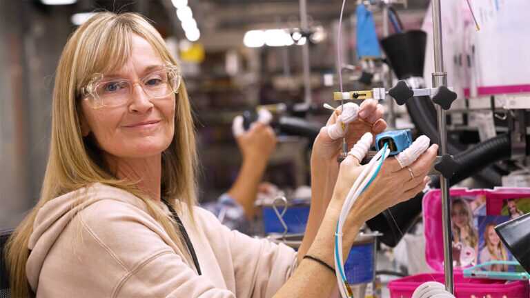 Gore Associate wearing safety glasses and gloves working with wiring at an assembly station.