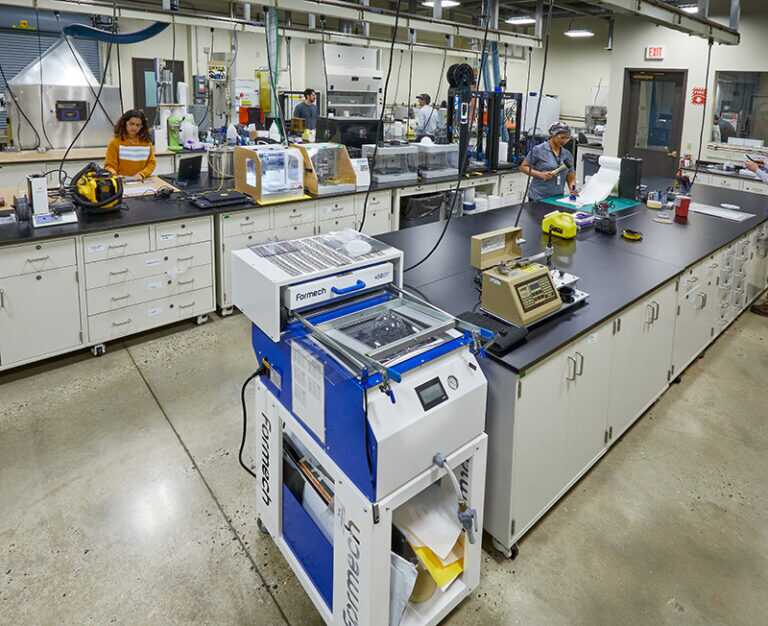 A wide shot of a Gore facility showing various workers operating at different work benches