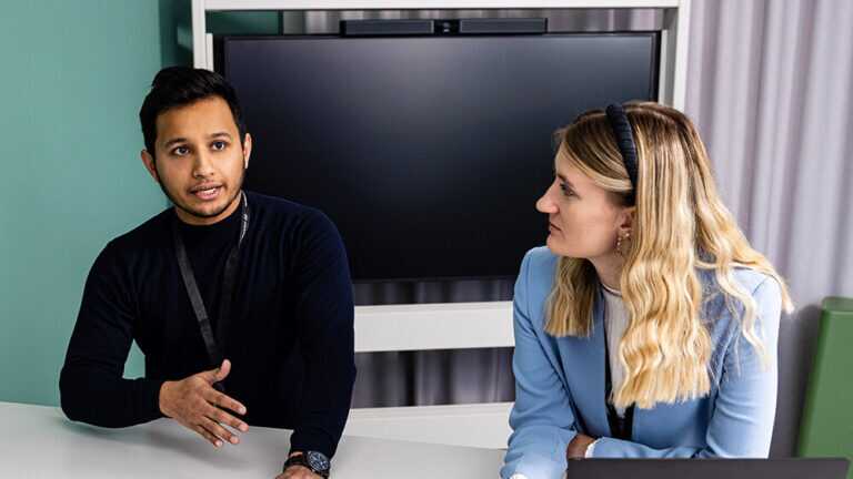 Colleagues sitting sitting next to each other having a discussion with team members off screen