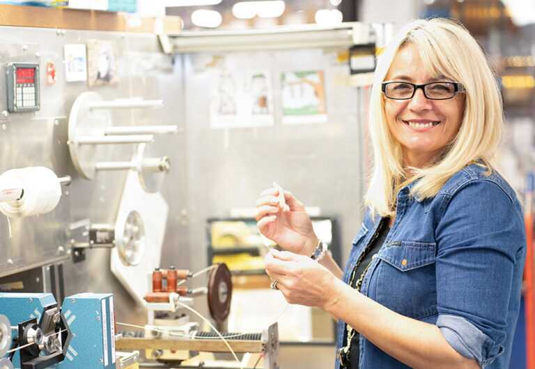Woman smiling in front of the camera while setting up a material using a specialized machine